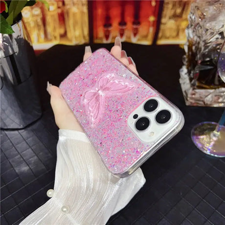 a woman holding a pink glitter phone case