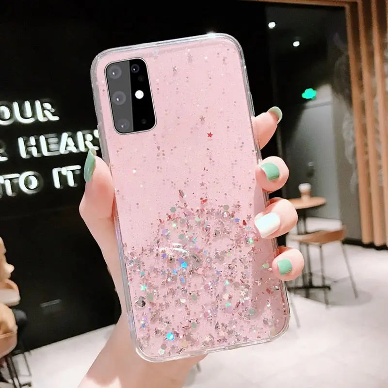 a woman holding a pink glitter phone case