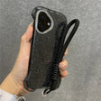 Glittery black phone case with a diamond-studded camera bezel and a black wrist lanyard.