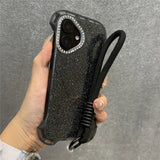Glittery black phone case with a diamond-studded camera bezel and a black wrist lanyard.