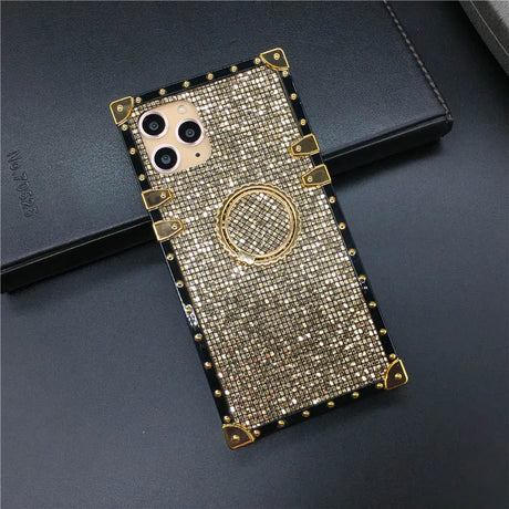 Glittery gold-colored phone case with a ring holder and decorative studs around the edges.