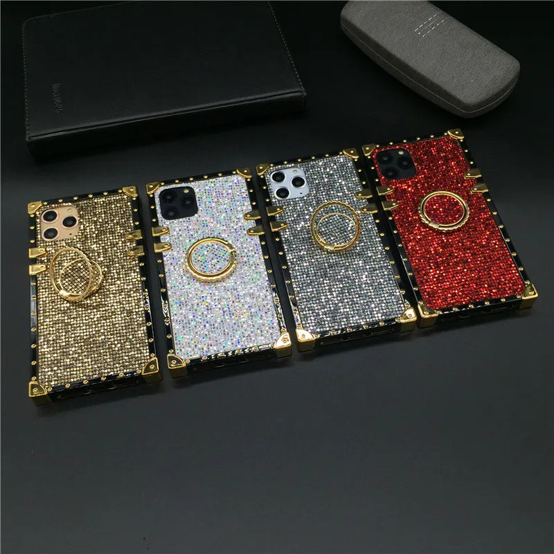 Glittery, jewel-encrusted smartphone cases in gold, silver, and red colors with ring holders.