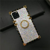 Glittery, rhinestone-encrusted smartphone case with a gold ring holder and corner accents.