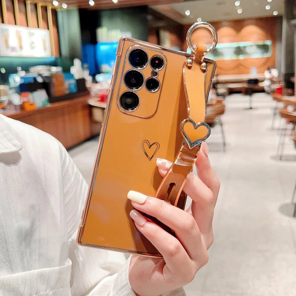 Gold-colored smartphone case with a heart-shaped strap.