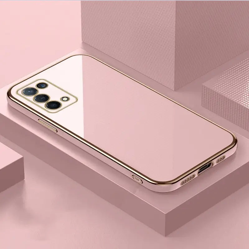a gold iphone case sitting on top of a pink surface
