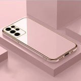 A gold iphone case sitting on top of a pink surface