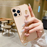 Gold iPhone with a pink heart-shaped charm accessory attached.