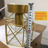 A gold metal candle holder with a measuring ruler