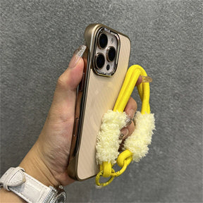 Gold-trimmed phone case with yellow fuzzy strap.