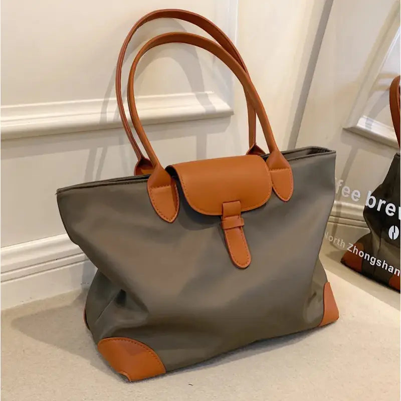 a gray and brown handbag with a brown handle