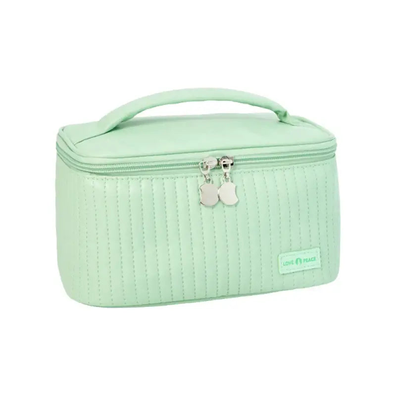 the green cosmetic case is made from a soft, quilted fabric