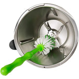 a green brush is in the bottom of a stainless steel bowl