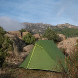 a green tent on a rocky mountain