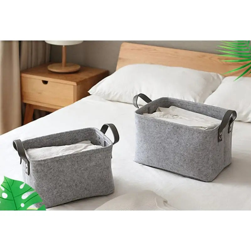 two grey felt storage baskets on a bed