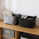 two grey felt storage baskets on a wooden shelf