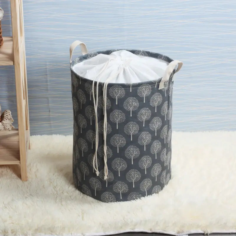 a grey fabric laundry basket with a tree print