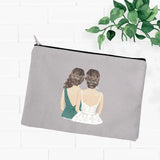 a grey zipper pouch with a drawing of two women sitting on the back of a white brick wall