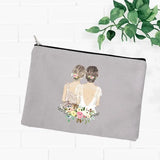 a grey zipper pouch with a watercolor illustration of a woman in a white dress
