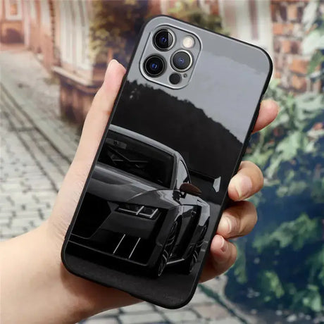 A hand holding a black iphone case with a car on it