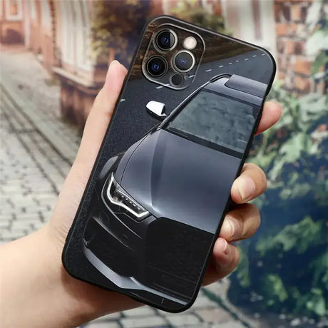 A hand holding a black iphone case with a car image on it