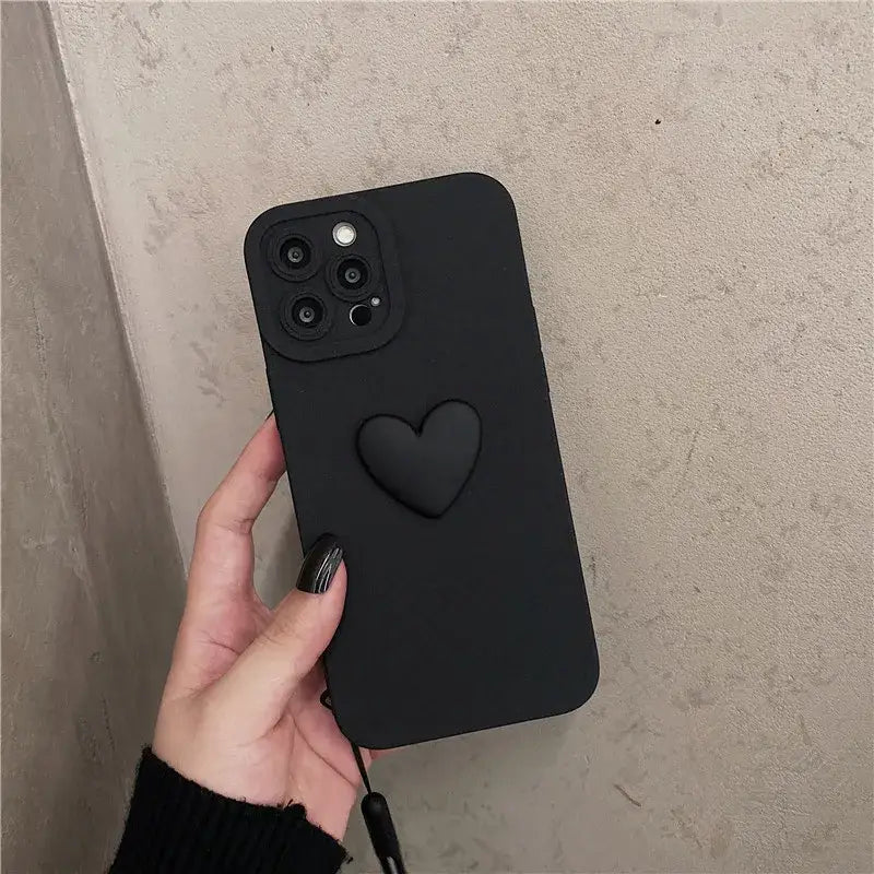 a hand holding a black iphone case with a heart on it