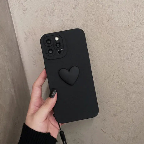 A hand holding a black iphone case with a heart on it