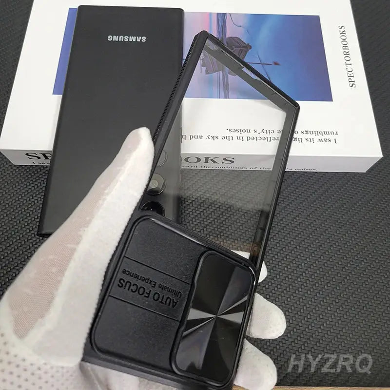 a hand holding a black phone with a box