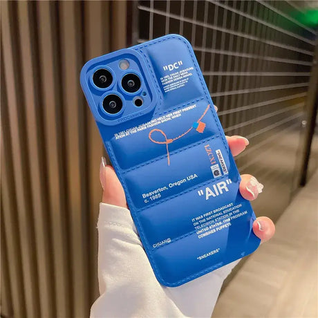 A hand holding a blue phone case with a logo on it