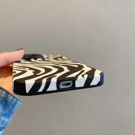 A hand holding a cell case with a zebra print