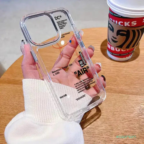 A hand holding a clear case with a white phone