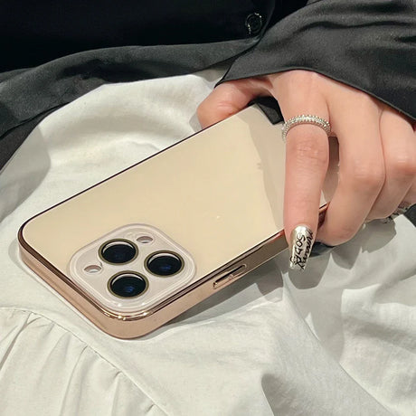 A hand holding a gold-colored smartphone with a three-lens camera and a matching gold case.