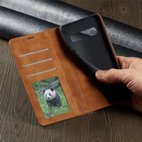 A hand holding a leather wallet case with a panda photo