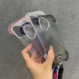 Hand holding multiple glittery, clear phone cases with rhinestone camera accents.