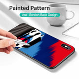 a hand holding a pen while painting a phone case