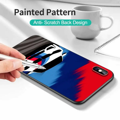 A hand holding a pen while painting a phone case