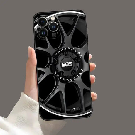 A hand holding a phone with a black wheel on it