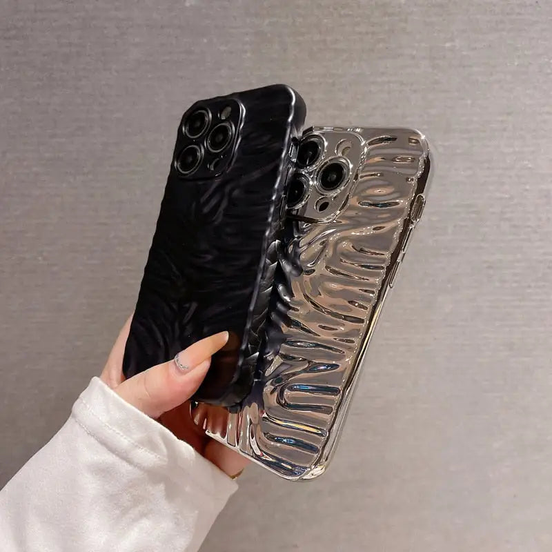 a hand holding a phone case with a black and silver design