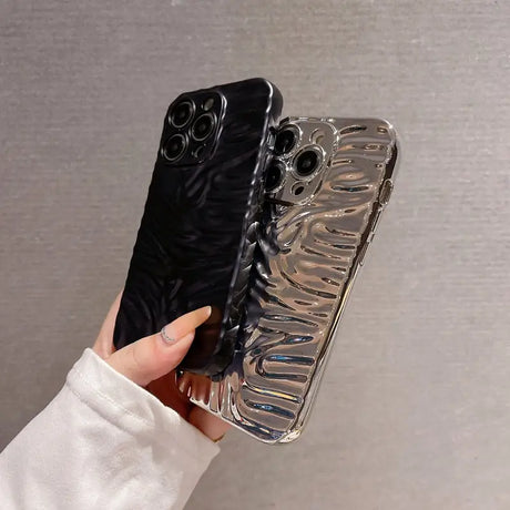 A hand holding a phone case with a black and silver design