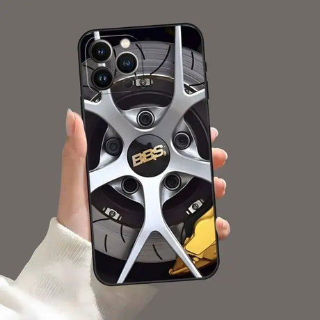 A hand holding a phone case with a car wheel