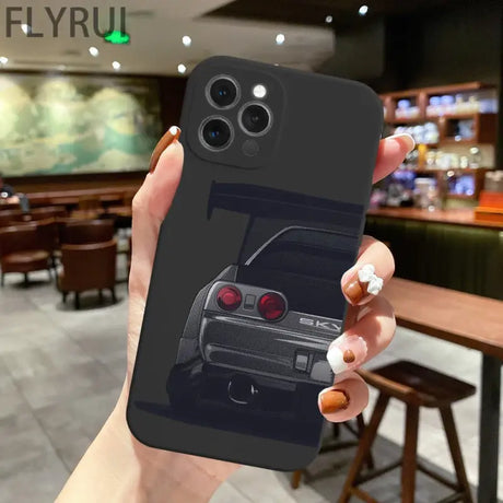 A hand holding a phone case with a car image on it