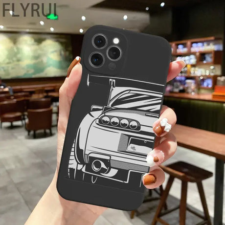 A hand holding a phone case with a car on it