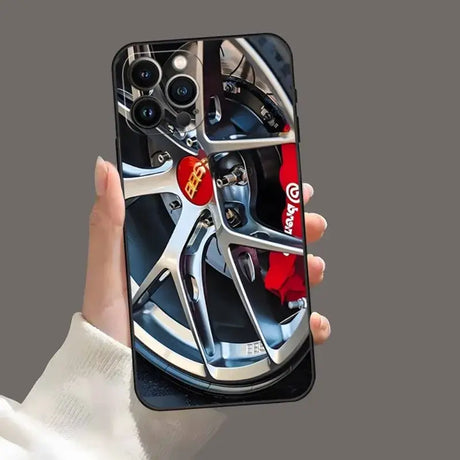 A hand holding a phone case with a ferrari wheel