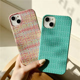A hand holding a phone case with a green and pink pattern