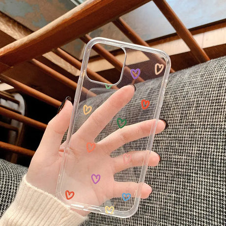 A hand holding a phone case with hearts painted on it