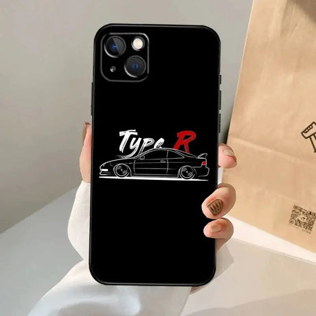 A hand holding a phone case with the logo of a car