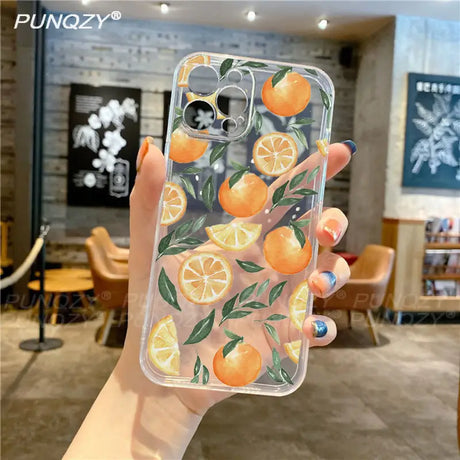 A hand holding a phone case with oranges on it