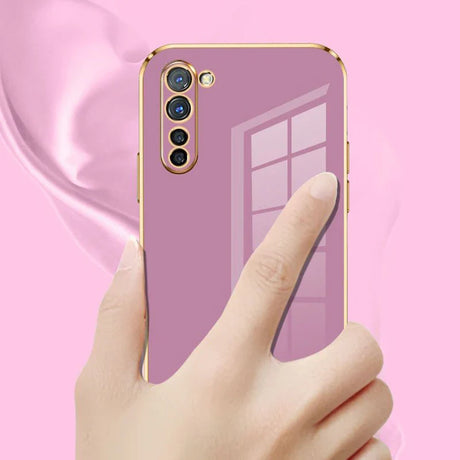 a hand holding a phone with a pink background