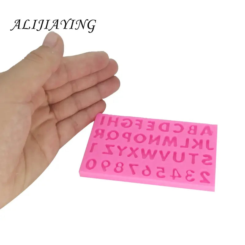 a hand holding a pink rubber rubber stamp with the letters