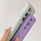 A hand holding a purple and green iphone case