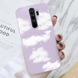 a hand holding a purple phone case with clouds in the sky